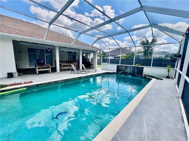 Screen enclosed in ground pool with waterfall and large patio for entertaining.