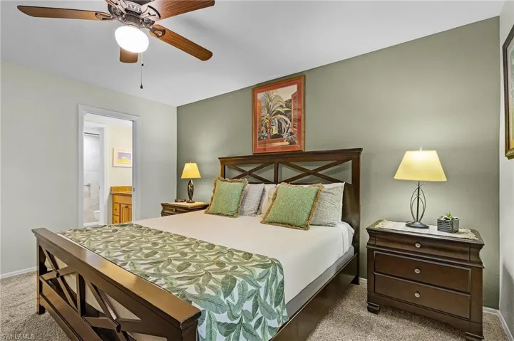 Carpeted bedroom featuring ensuite bath and ceiling fan