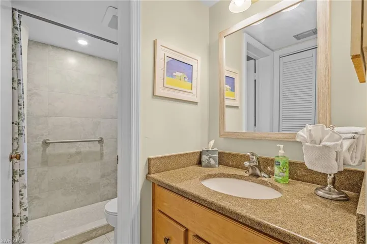 Bathroom with tile patterned floors, vanity, toilet, and a tile shower
