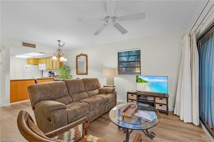 Living room with light hardwood / wood-style floors and ceiling fan with notable chandelier