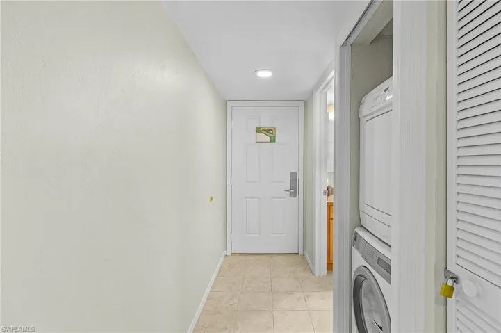 Laundry room featuring stacked washer / dryer and light tile patterned flooring