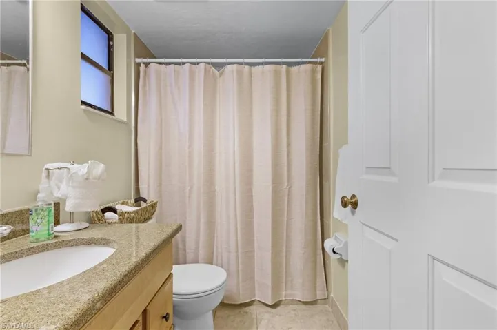 Bathroom featuring tile patterned floors, walk in shower, vanity, and toilet