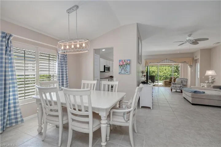 Tiled dining area featuring lofted ceiling and ceiling fan with notable chandelier