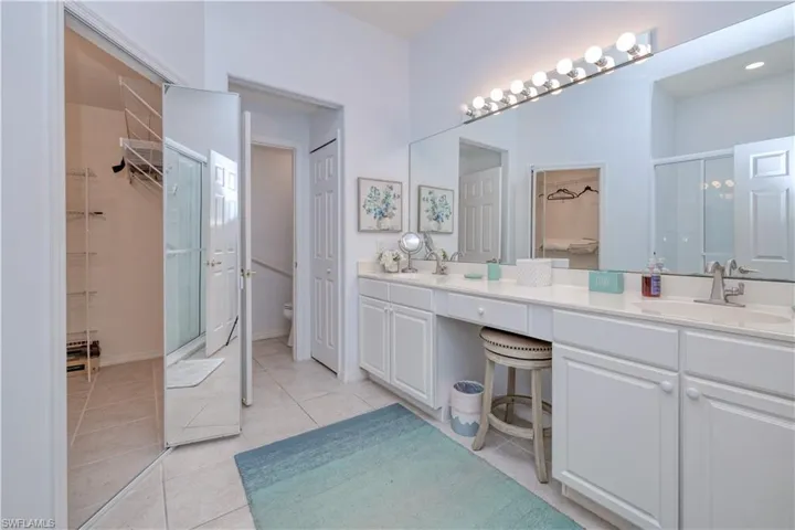 Bathroom with dual bowl vanity, toilet, and tile floors
