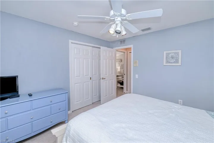 Bedroom with a closet, ceiling fan, and light colored carpet
