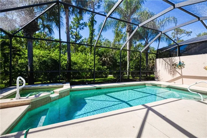 View of swimming pool with a patio, glass enclosure, and an in ground hot tub