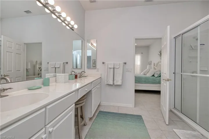 Bathroom with dual sinks, tile floors, an enclosed shower, large vanity, and lofted ceiling
