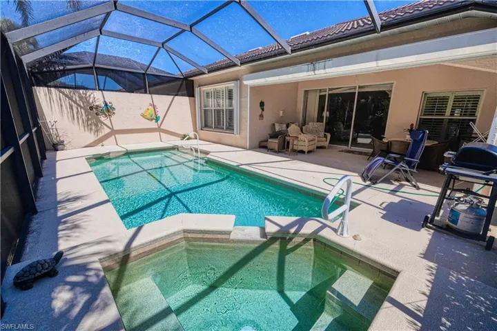 View of swimming pool featuring glass enclosure and a patio area