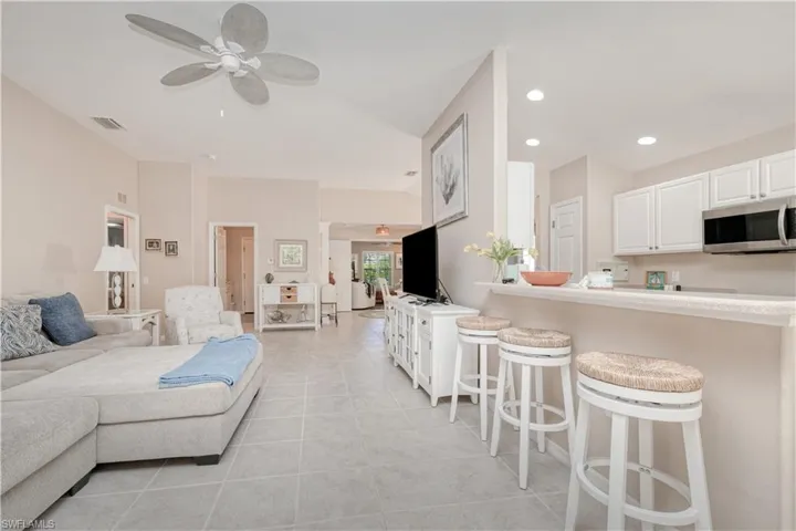 Living room with ceiling fan and light tile floors