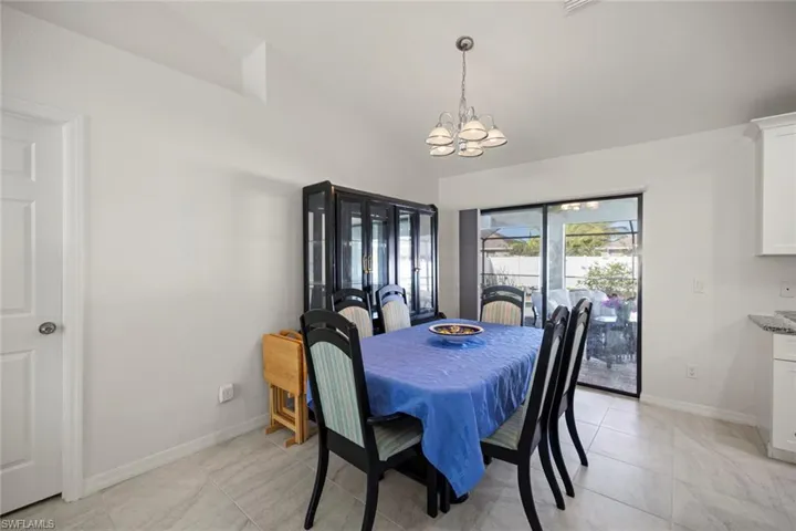 Dining area featuring light tile patterned floors, baseboards, an inviting chandelier, and lofted ceiling