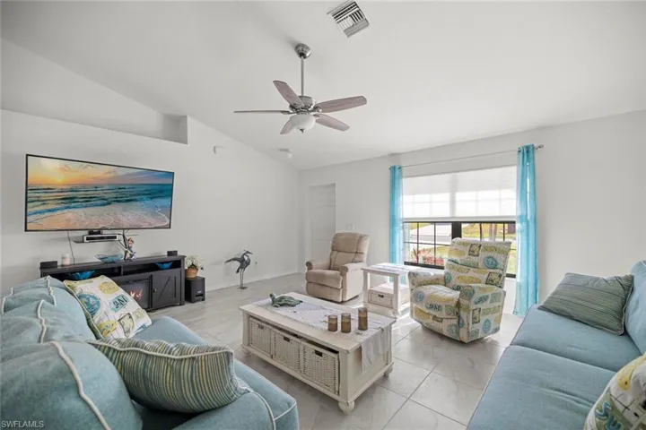 Living area featuring visible vents, baseboards, ceiling fan, light tile patterned flooring, and lofted ceiling