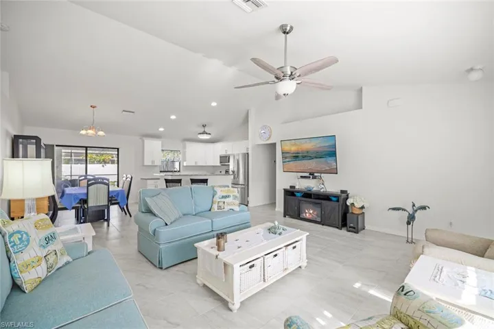 Living room featuring baseboards, recessed lighting, visible vents, high vaulted ceiling, and ceiling fan with notable chandelier