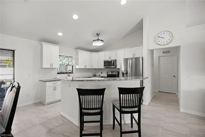 Kitchen with white cabinetry, a center island, appliances with stainless steel finishes, and a breakfast bar area