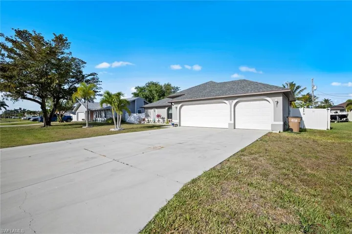 View of front facade with a garage, a front lawn, stucco siding, and concrete driveway