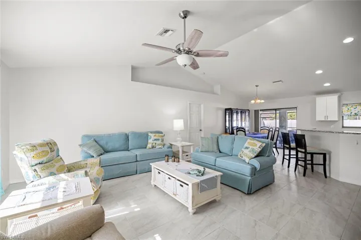 Living room featuring recessed lighting, visible vents, ceiling fan with notable chandelier, and vaulted ceiling