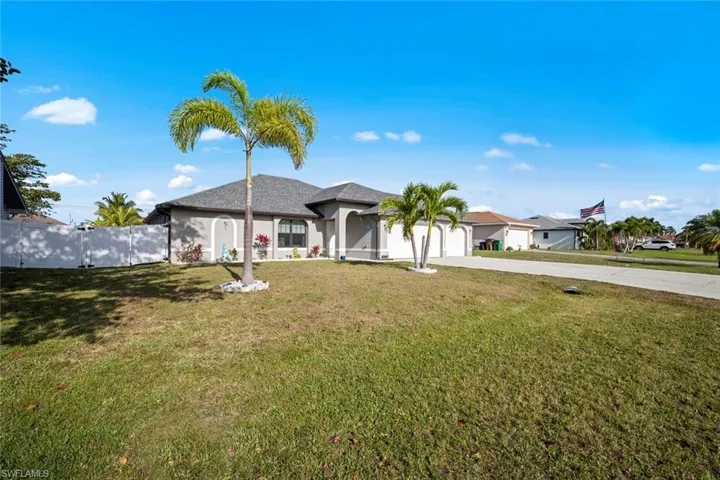 View of front facade with concrete driveway, stucco siding, a front lawn, an attached garage, and fence