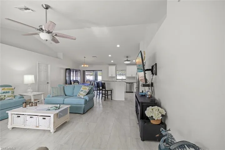 Living room featuring ceiling fan, lofted ceiling, visible vents, and recessed lighting