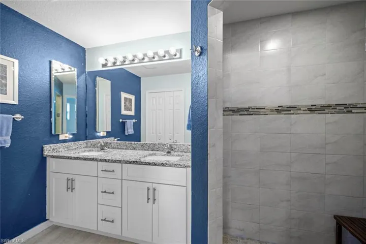Bathroom featuring wood finished floors, double vanity, a sink, and a textured wall