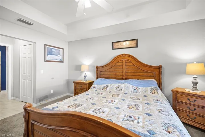 Carpeted bedroom Master bedroom featuring a tray ceiling, ceiling fan, baseboards, and visible vents