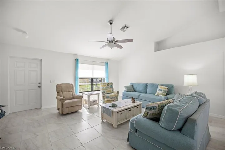 Living area with ceiling fan, baseboards, lofted ceiling, and visible vents