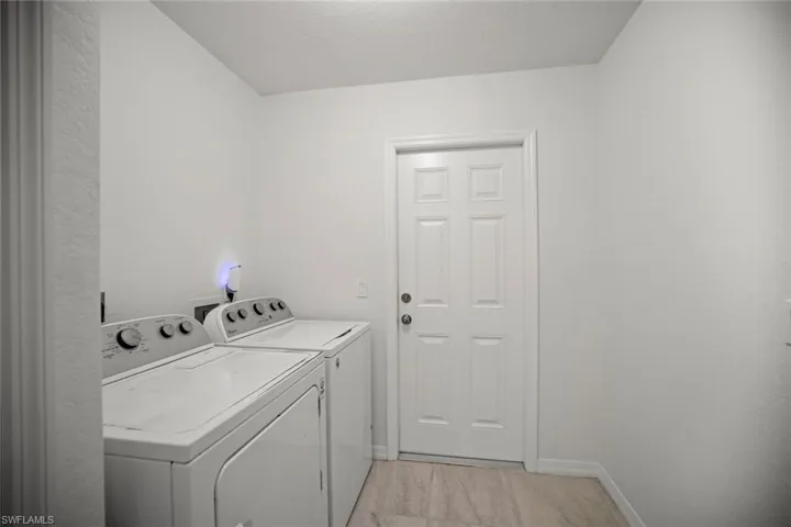 Clothes washing area featuring laundry area, baseboards, and washer and clothes dryer