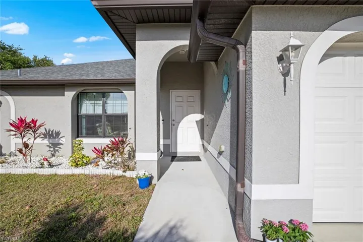 Doorway to property with an attached garage, roof with shingles, and stucco siding