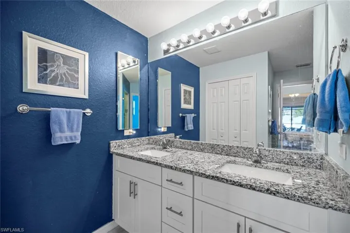 Bathroom with double vanity, a textured wall, and a sink