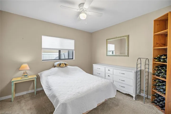 Bedroom with light colored carpet, baseboards, and a ceiling fan
