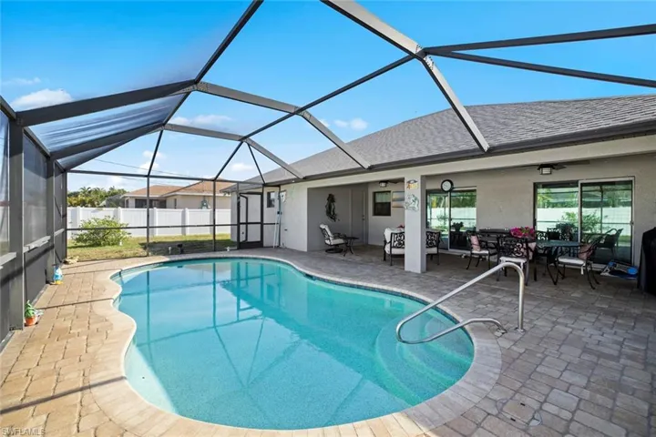View of swimming pool featuring glass enclosure, a fenced in pool, a patio, and outdoor dining area
