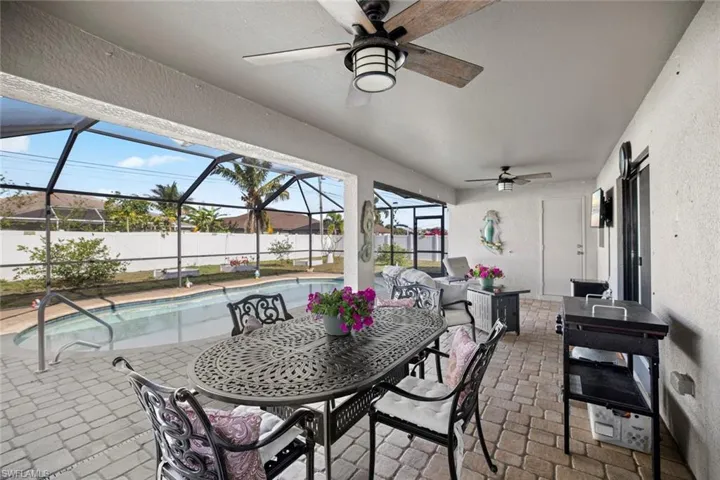 View of patio with ceiling fan, a fenced in pool, fence, and glass enclosure