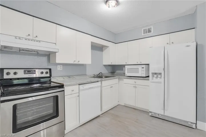 Kitchen with sink, white appliances, and white cabinetry