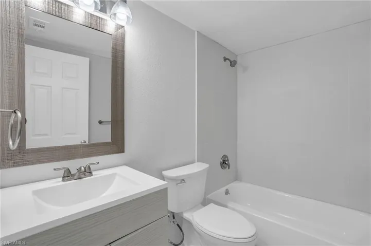 Full bathroom with tiled shower / bath, vanity, and toilet