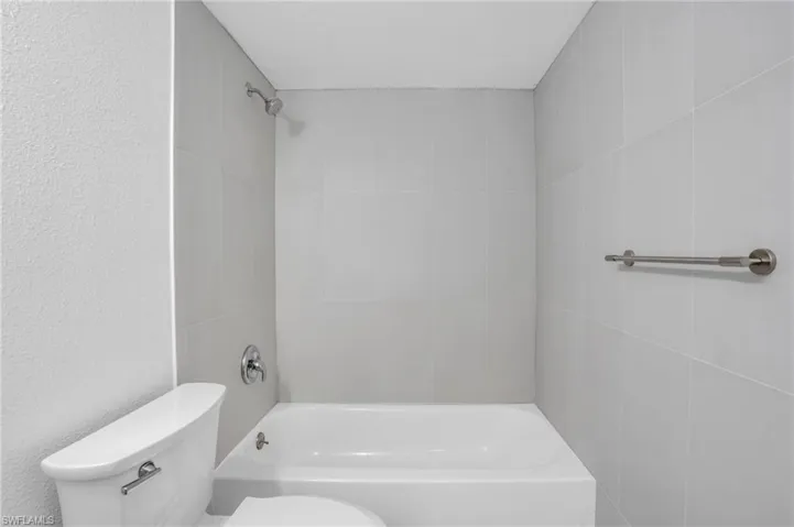 Bathroom with tiled shower / bath and toilet