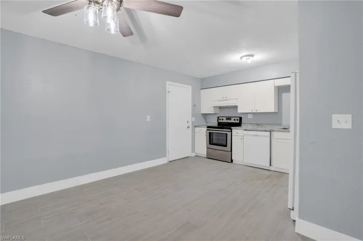 Kitchen with stainless steel electric stove, ceiling fan, dishwasher, and white cabinetry