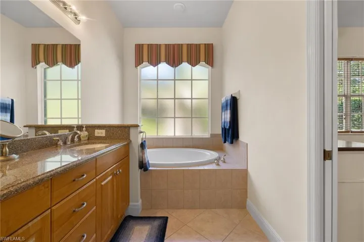 Primary ensuite bathroom showing soaking tub, dual vanity, windows looking onto the preserve area.