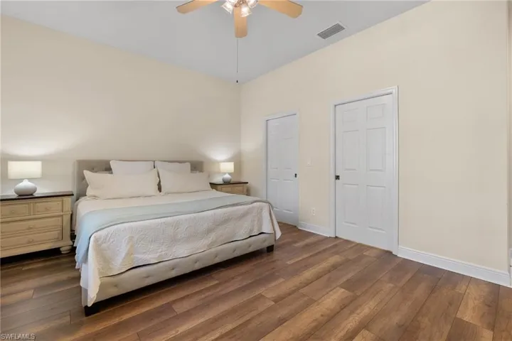 Primary Bedroom featuring wood-type flooring, ceiling fan, and two walk-in closets