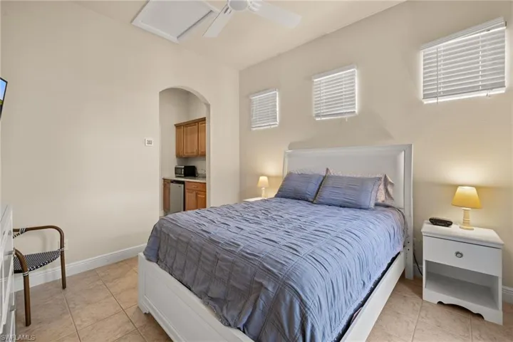 Cabana bedroom with additional sun filtering windows side table, dresser and TV.