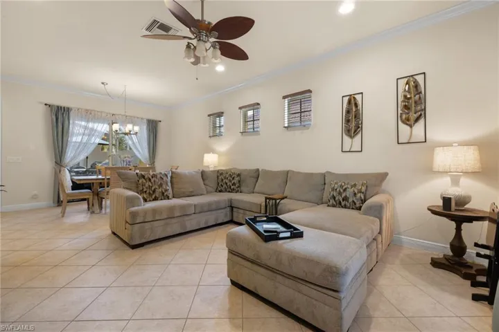 Great Room with light tile patterned flooring, molding, windows and sliding doors onto courtyard.