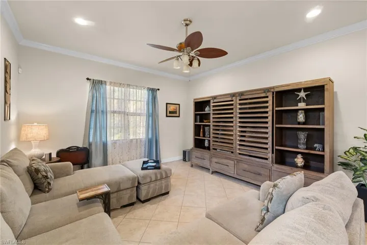 Great Room featuring light tile patterned floors, ornamental molding, and ceiling fan. Looking onto rear preserve view.