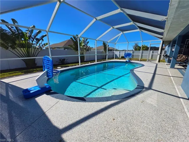 View of swimming pool featuring glass enclosure, a patio, a fenced backyard, and a sunroom