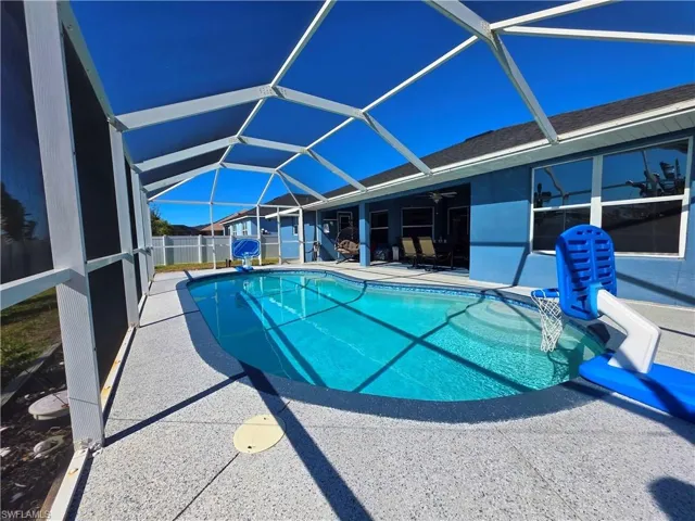 Outdoor pool featuring a sunroom, glass enclosure, and a patio
