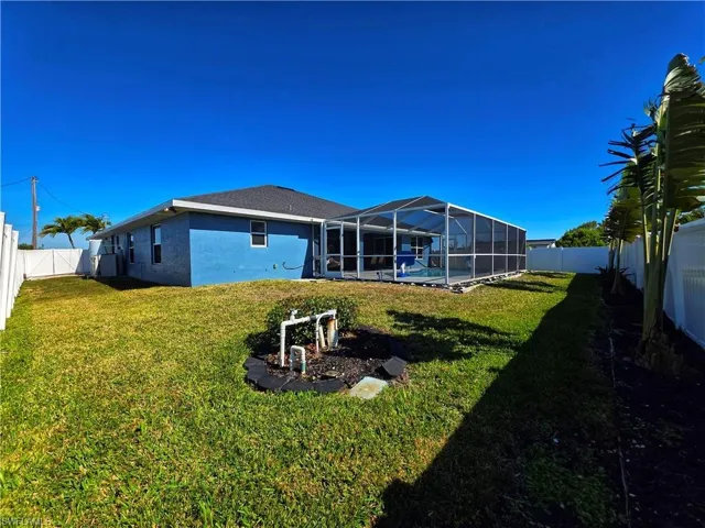 Rear view of house with a sunroom, a fenced backyard, a lanai, and a swimming pool