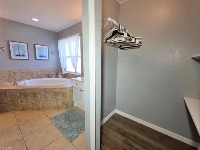 Full bathroom with vanity, a garden tub, and dark tile patterned flooring