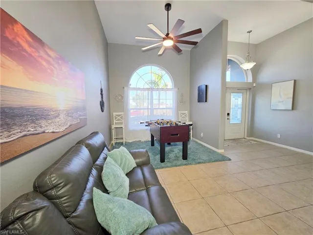 Playroom with ceiling fan, tile patterned flooring, plenty of natural light, and a towering ceiling