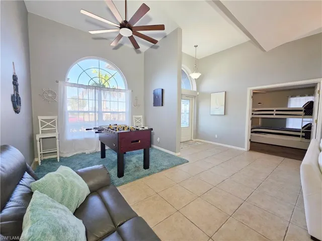 Playroom featuring light tile patterned floors, ceiling fan, and a towering ceiling