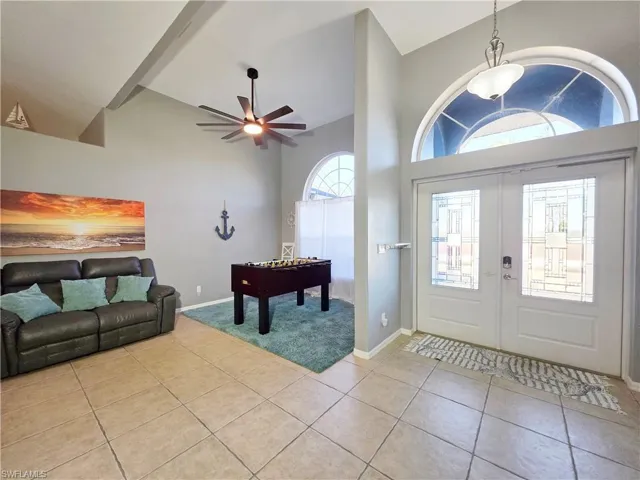 Entryway with a ceiling fan, light tile patterned floors, french doors, and high vaulted ceiling