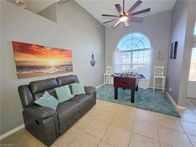 Game room featuring high vaulted ceiling, light tile patterned floors, and ceiling fan