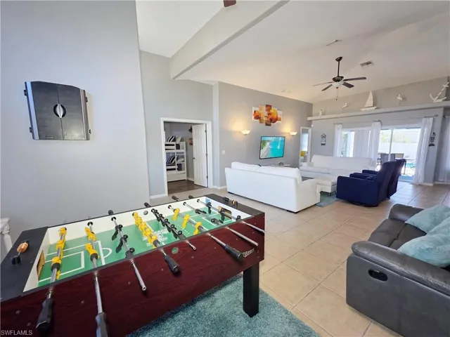 Recreation room featuring light tile patterned floors, a ceiling fan, and high vaulted ceiling