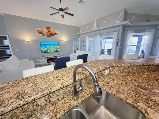 Kitchen with dark stone counters, open floor plan, lofted ceiling, and healthy amount of natural light
