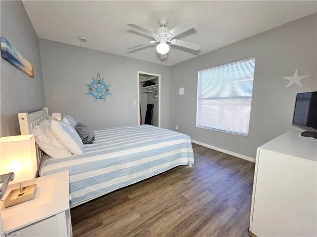 Bedroom featuring a spacious closet, a ceiling fan, and dark wood-style flooring